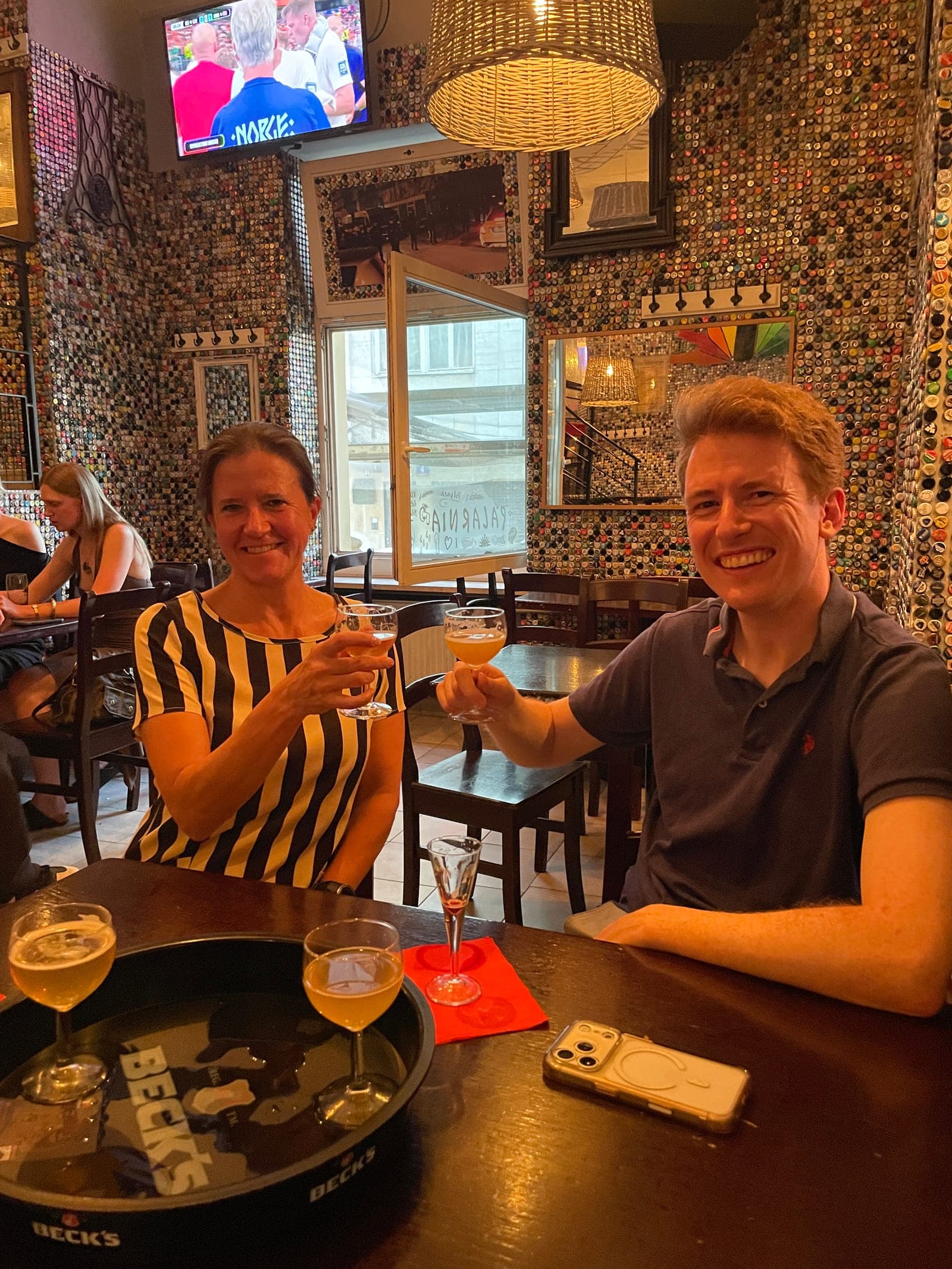 Two guests toasting with craft beer flights on a private Tasty Trails tour in a Warsaw bottle-cap bar