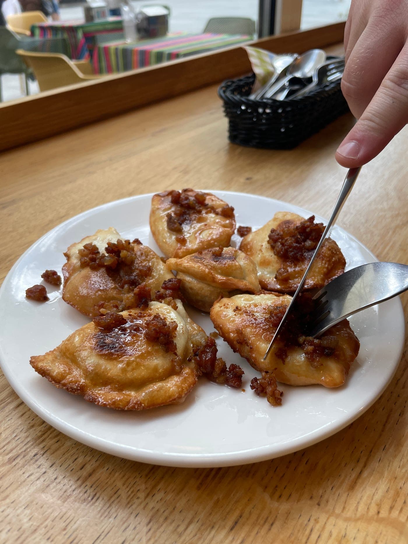 Golden pan-fried pierogi topped with crispy skwarki at a Warsaw pierogi spot