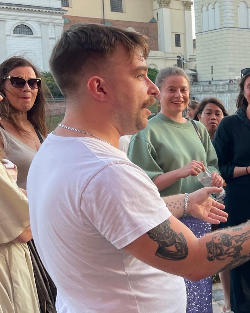 Michał, Tasty Trails co-founder, telling stories to a tour group on Castle Square in Warsaw
